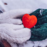 Image of hands holding a heart in the snow