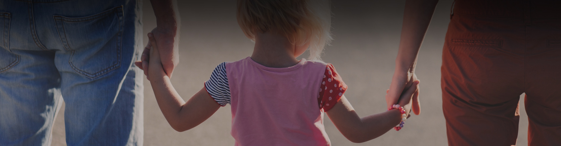 Photo of a young girl holding her parents hands