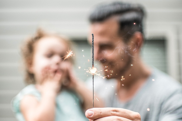 Photo of a father with their child holding a sparkler