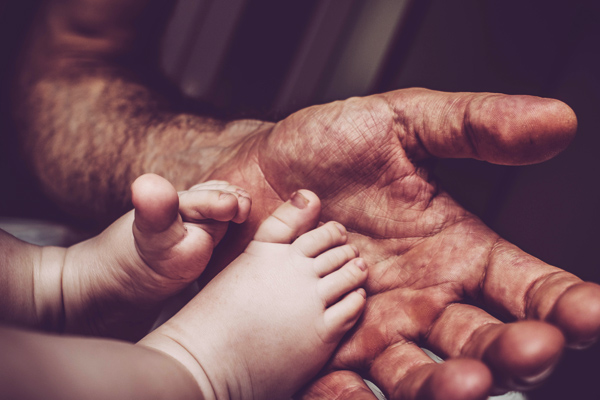 Closeup photo of an old man holding a baby's feet