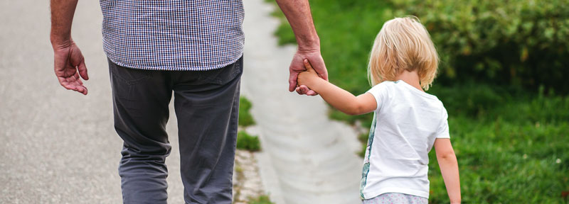 Photo of father and daughter holding hands while walking