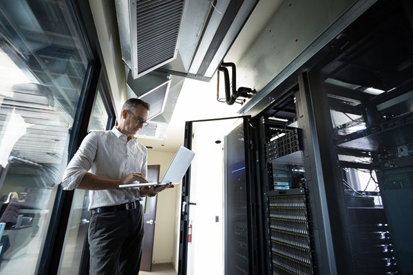 A photo of a man working on computer in a server room