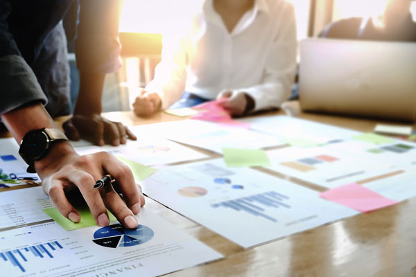 A photo of people reviewing graphs and reports on a table