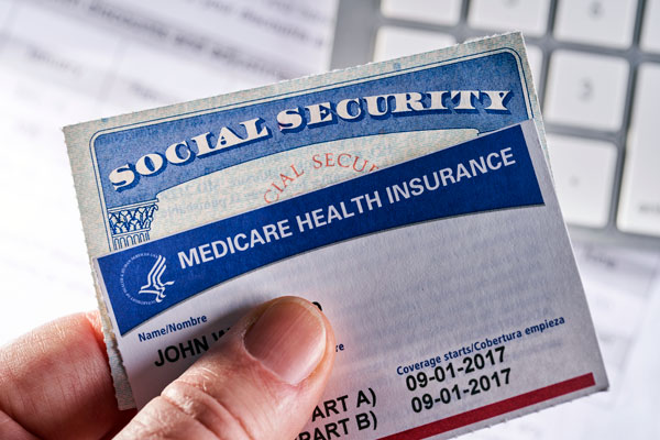 A photo of a hand holding up social security and medicare health insurance cards