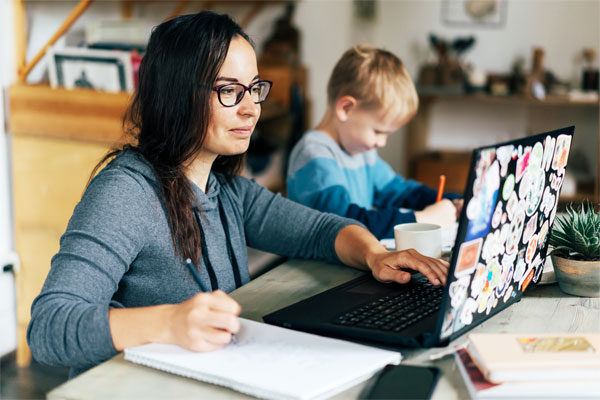 Photo of a working mother at home watching her children while on her laptop