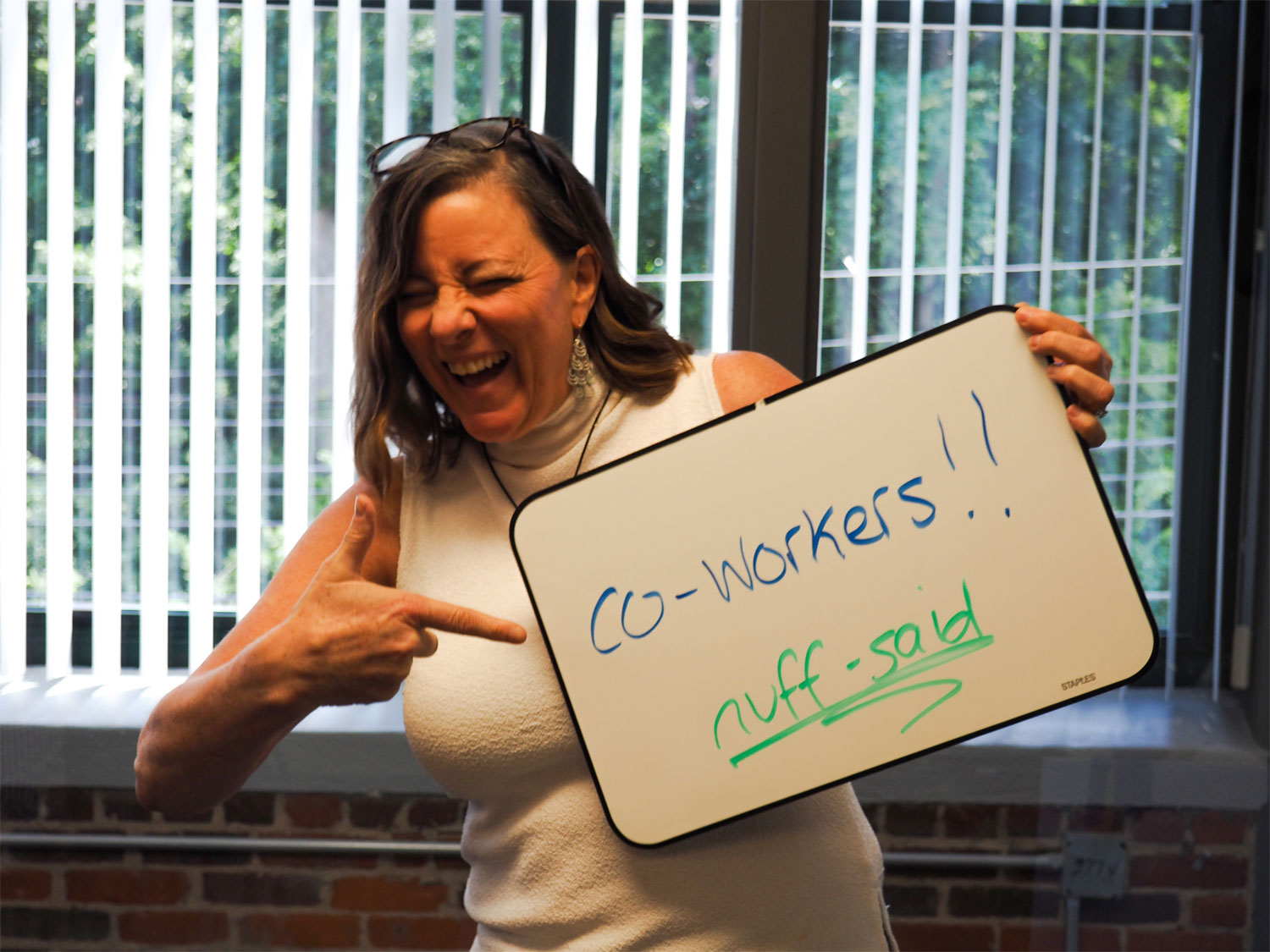 Nancy Poulin, Account Manager, holding a whiteboard with the reasons she loves working at Clark!