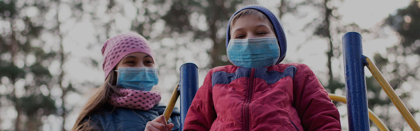 A photo of two kids wearing masks on a school yard