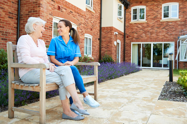 Photo of a long-term care specialist sitting on a bench with an elderly woman